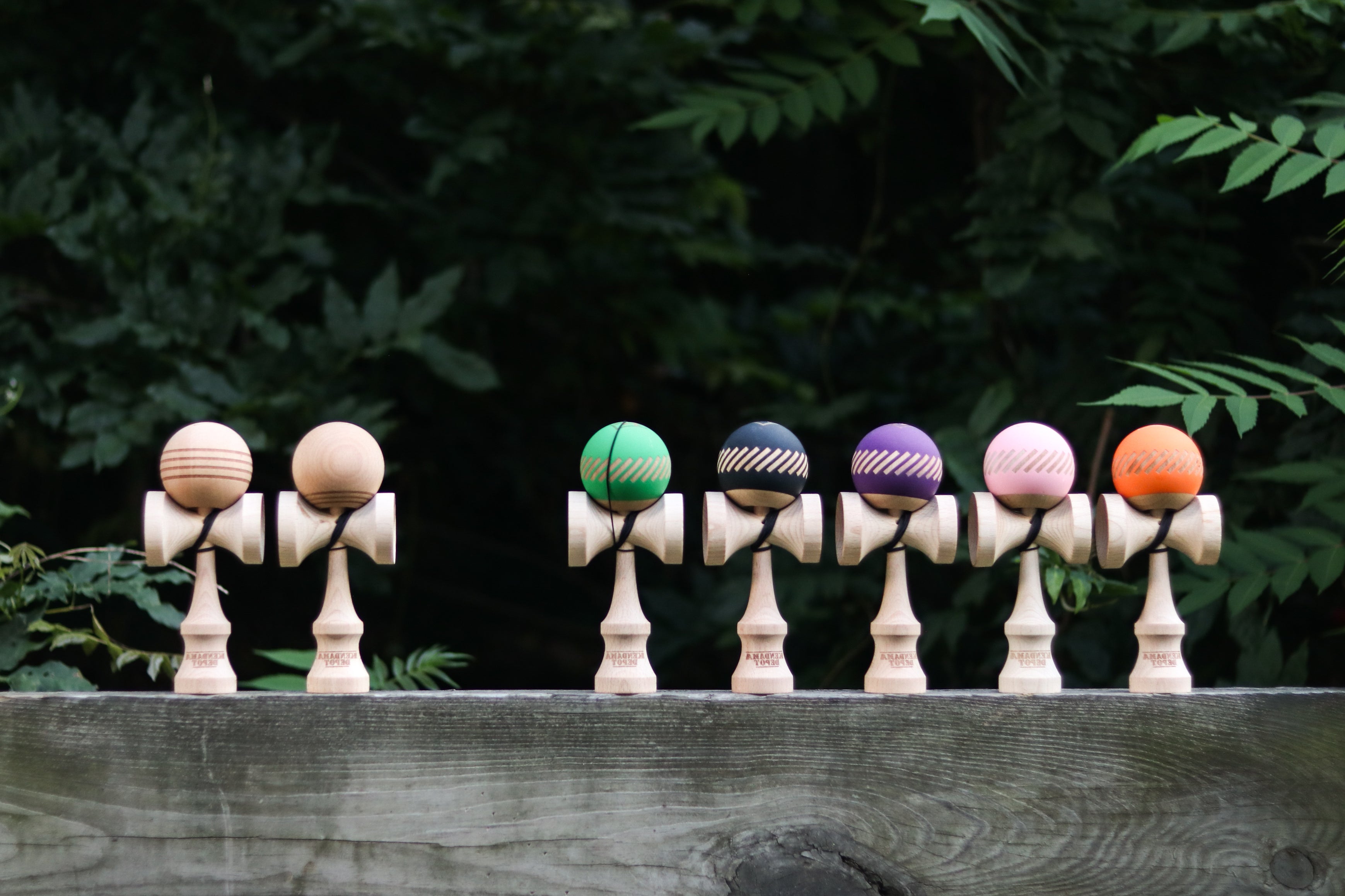 Seven STOCK complete kendamas: two natural designs plus black, green, purple, pink, and orange